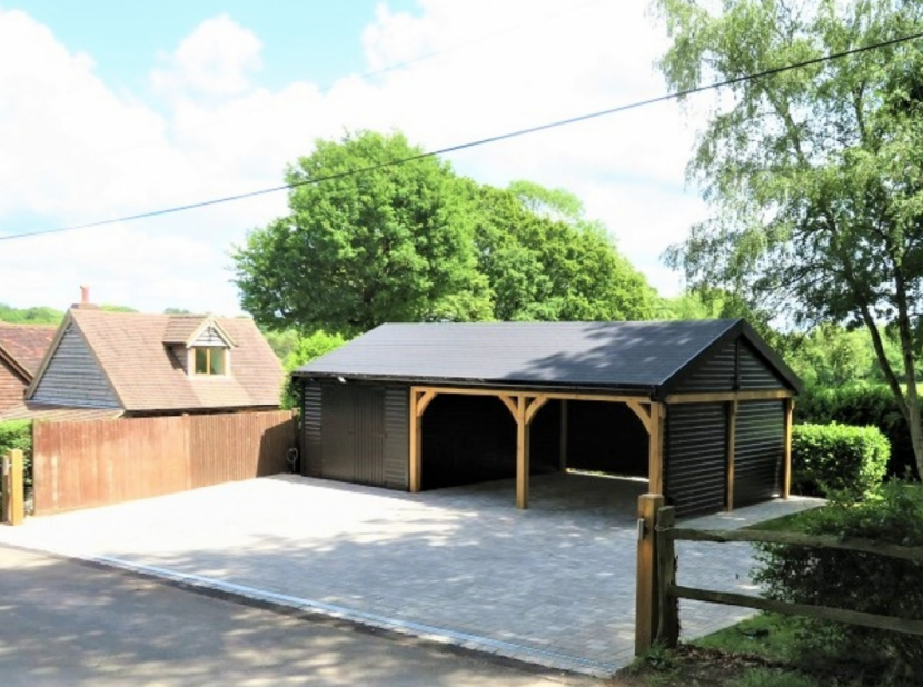 Black wooden garden shed with births for cars